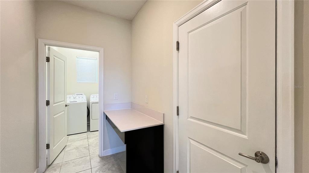 A laundry room with a white countertop and a doorway leading to a washer and dryer — 3029 PRELUDE LANE, KISSIMMEE, FL