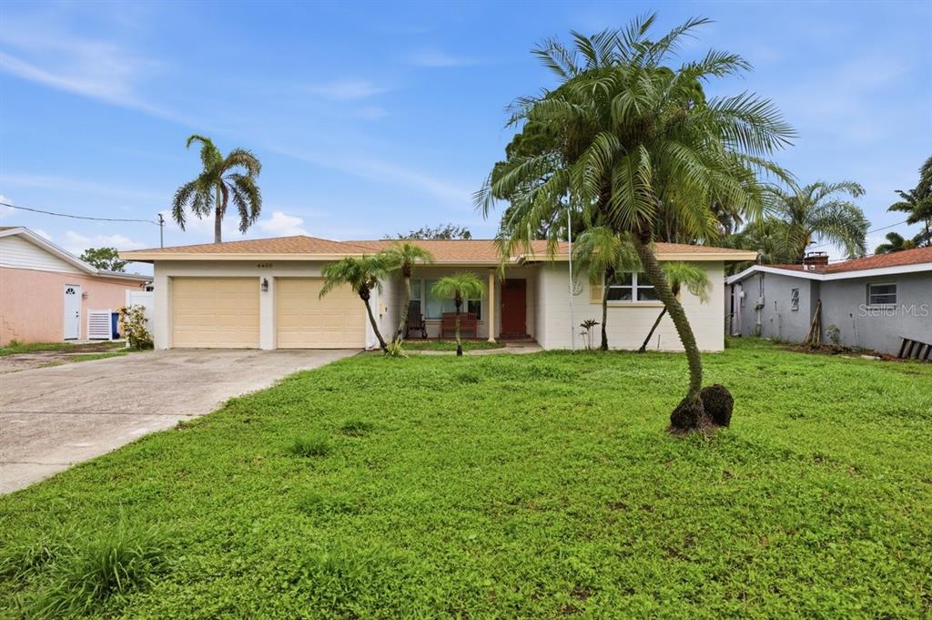 A single-story house with a two-car garage, palm trees, and a grassy front yard — 4400 HUNTINGTON STREET NE, ST PETERSBURG, FL