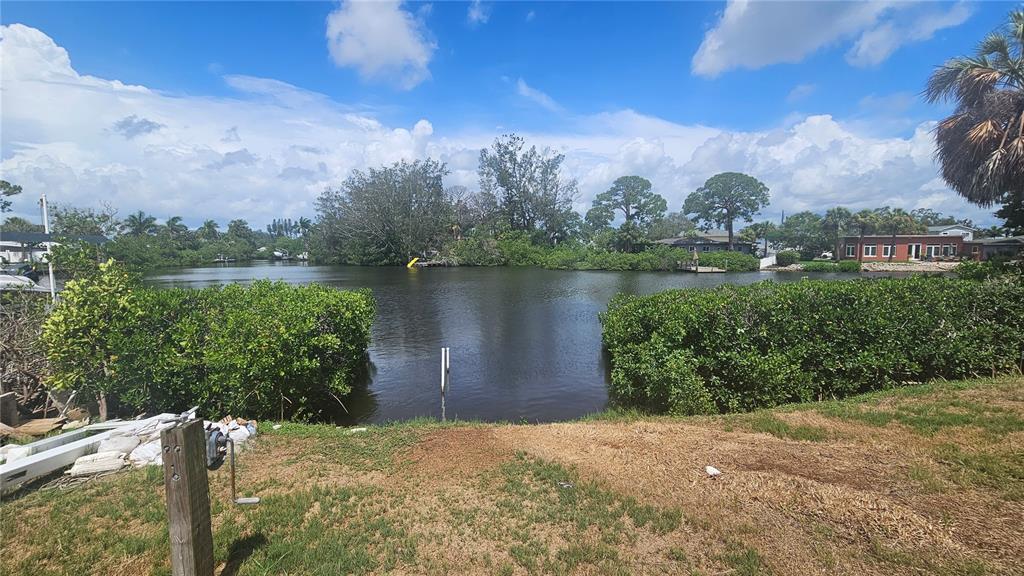 A view of a canal from a grassy backyard with dense green bushes on both sides — 4400 HUNTINGTON STREET NE, ST PETERSBURG, FL