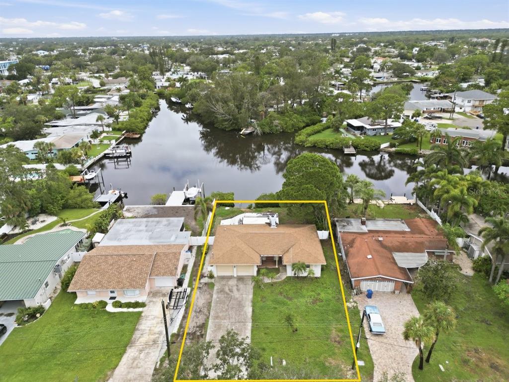 An aerial view shows a single-story house with a brown roof and a waterfront backyard — 4400 HUNTINGTON STREET NE, ST PETERSBURG, FL