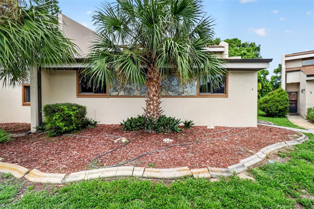 A tan, single-story house with a slanted roof, palm trees, and a concrete walkway — 7025 COGNAC DRIVE UNIT 4, NEW PORT RICHEY, FL