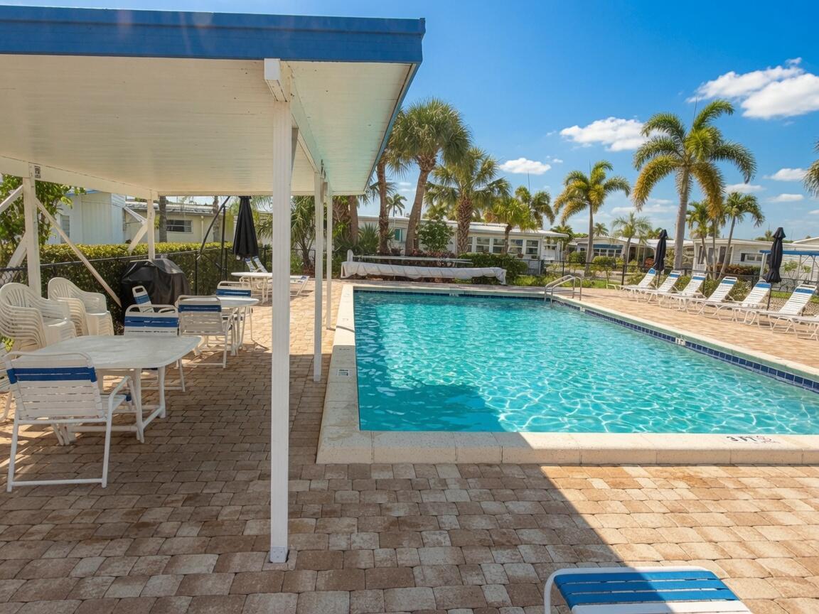 A rectangular swimming pool sits on a paved patio next to a covered seating area — 3500 S Kanner Highway Lot 31, Stuart FL 34994, STUART, FL