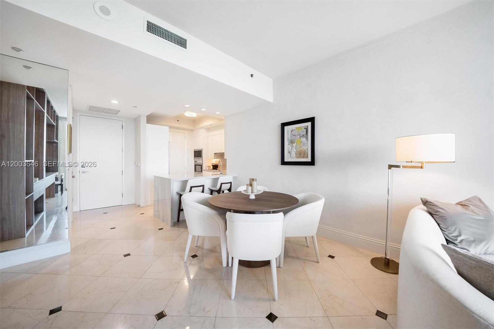 A dining area with a round table and white chairs sits near a modern kitchen — 100 S Pointe Dr # 702, Miami Beach FL 33139, MIAMI BEACH, FL