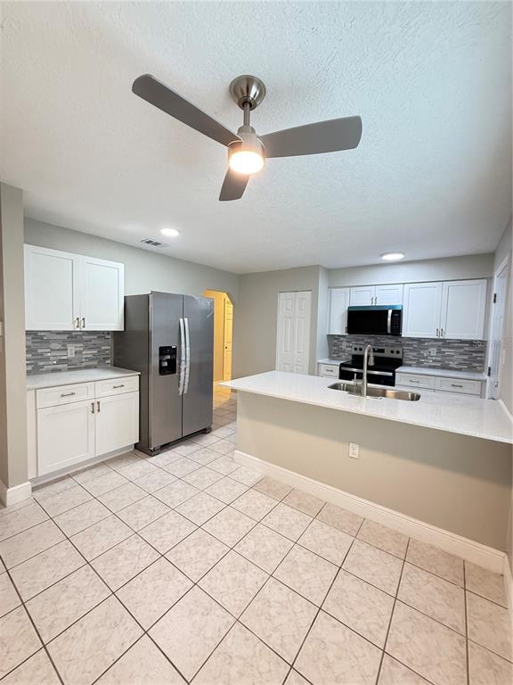 A kitchen features white cabinets, stainless steel appliances, a breakfast bar, and tiled flooring — 221 SHERRY AVE, WINTER SPRINGS, FL