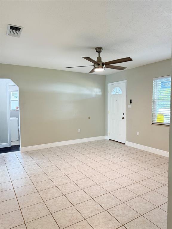 A living room with light-colored tile flooring, a ceiling fan, and a white entry door — 221 SHERRY AVE, WINTER SPRINGS, FL