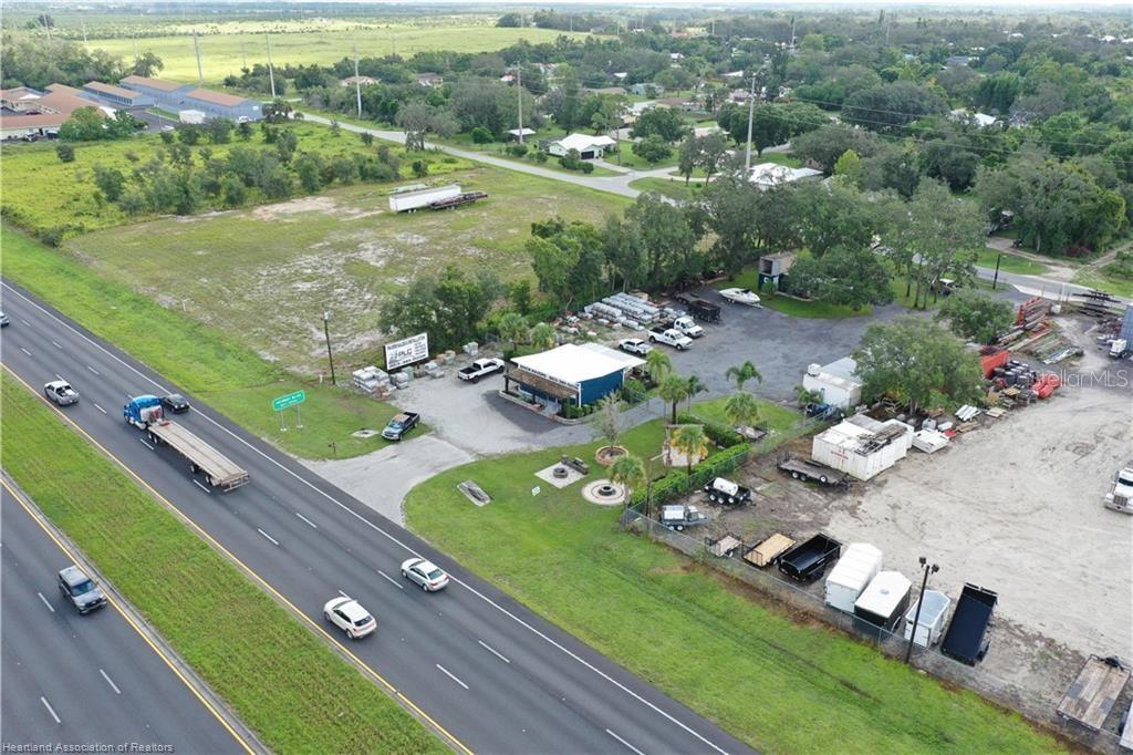 An aerial view shows a commercial property with a building and storage yard beside a highway — 6750 US HIGHWAY 27 S, SEBRING, FL
