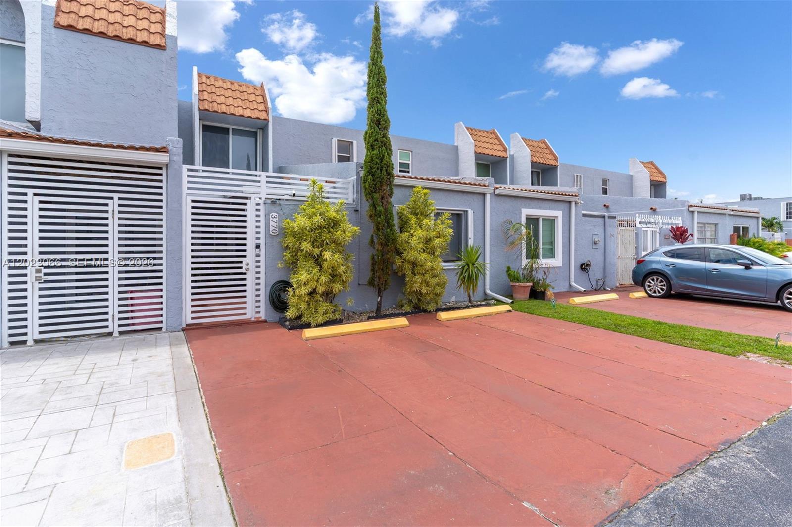 A row of gray townhouses features red concrete driveways and small front courtyards — 3770 W 8th Ln # 27, Hialeah FL 33012, HIALEAH, FL