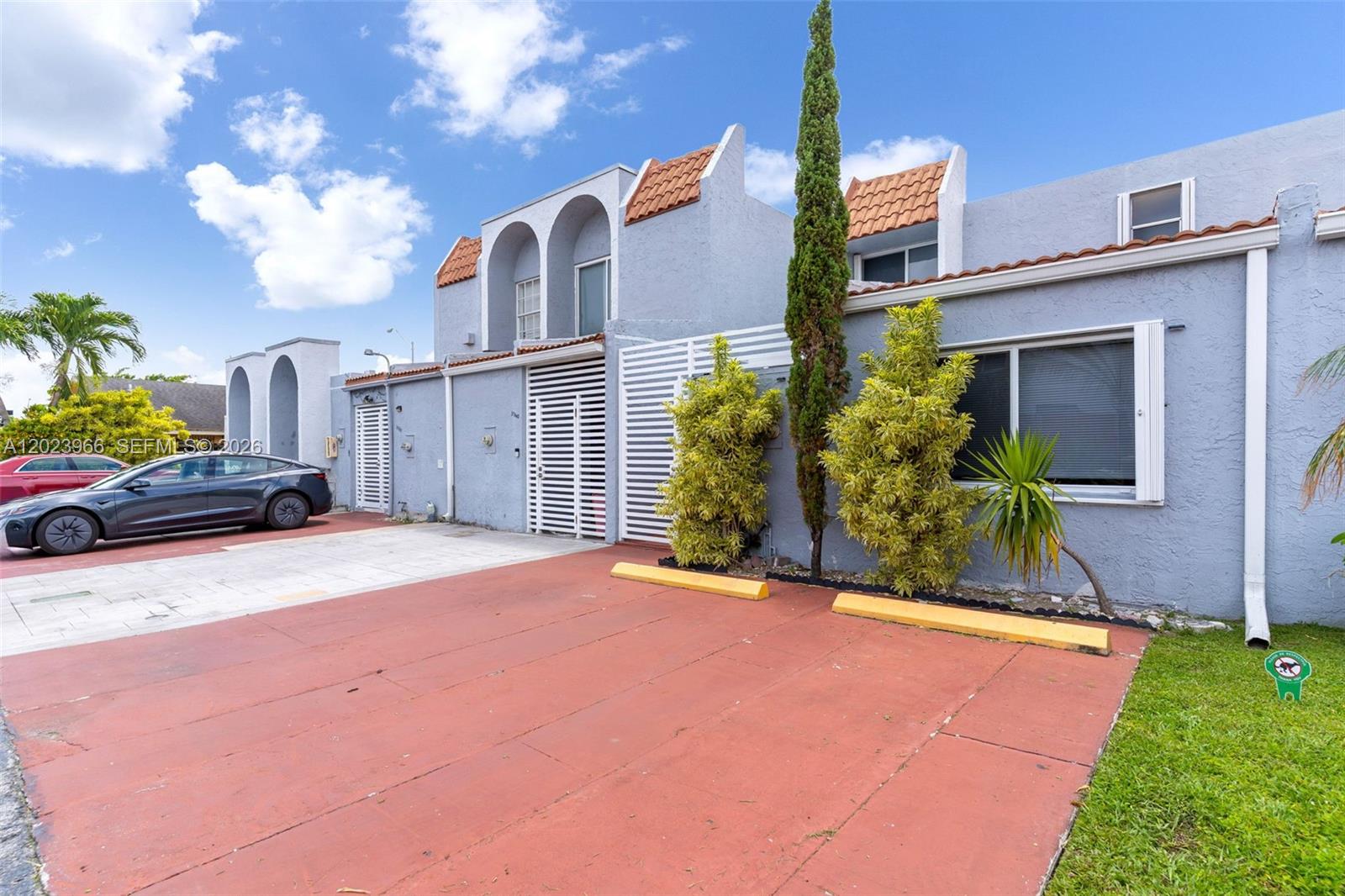 A two-story gray townhouse features a red concrete driveway and a small front yard — 3770 W 8th Ln # 27, Hialeah FL 33012, HIALEAH, FL
