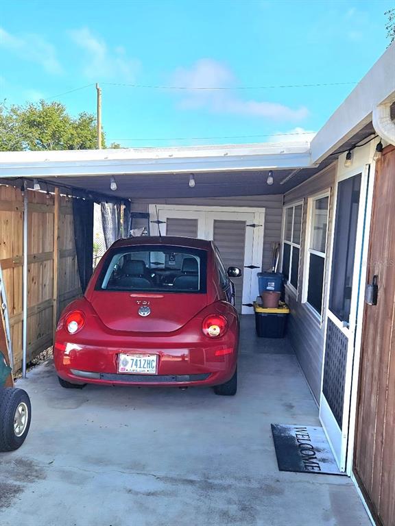 A red Volkswagen Beetle is parked under a covered carport attached to a house — 6619 NEW JERSEY STREET, BRADENTON, FL