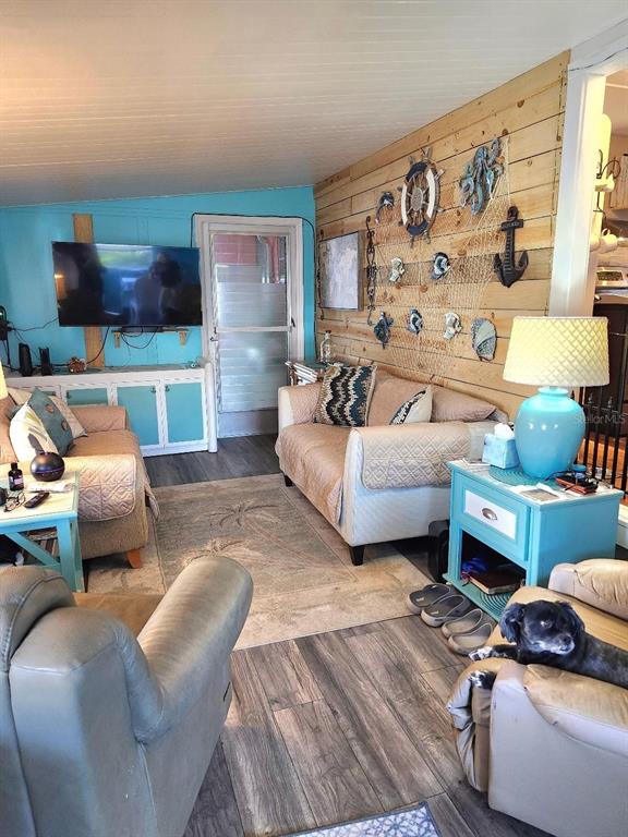 A living room features a wood-paneled wall, blue accent wall, and a small dog resting — 6619 NEW JERSEY STREET, BRADENTON, FL