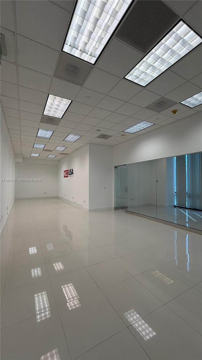 An empty office space features white tile flooring, white walls, and a drop ceiling — 1200 Brickell Ave # 200, Miami FL 33131, MIAMI, FL