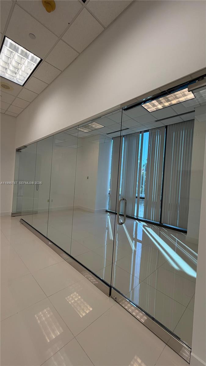 A modern office space features glass walls, a glass door, and white tiled flooring — 1200 Brickell Ave # 200, Miami FL 33131, MIAMI, FL
