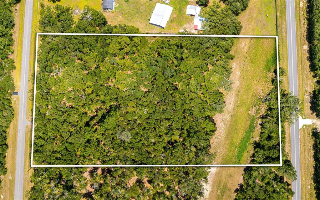 An aerial view shows a rectangular, wooded plot of land bordered by two roads — Lot 5 SW MEADOWLANDS DRIVE, LAKE CITY, FL