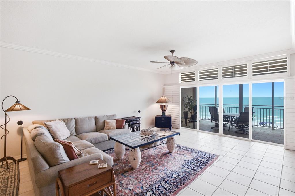 A living room features a sectional sofa, a glass coffee table, and sliding doors overlooking the ocean — 2 15TH AVENUE UNIT 303, INDIAN ROCKS BEACH, FL