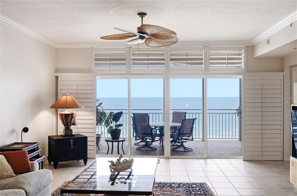 A living room with tile floors and a ceiling fan overlooks a balcony and ocean — 2 15TH AVENUE UNIT 303, INDIAN ROCKS BEACH, FL
