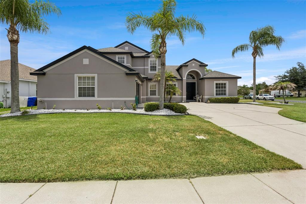 A two-story gray house with a large front lawn, palm trees, and a concrete driveway — 3480 FOREST RIDGE LANE, KISSIMMEE, FL