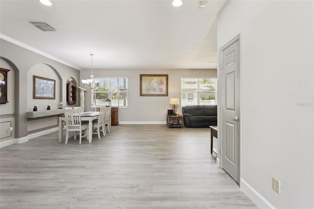 A dining area and living space with light wood-look flooring and neutral walls — 3480 FOREST RIDGE LANE, KISSIMMEE, FL