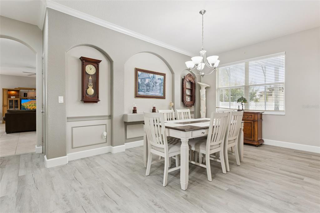 A dining room features a white table with chairs, arched wall niches, and wood-look flooring — 3480 FOREST RIDGE LANE, KISSIMMEE, FL