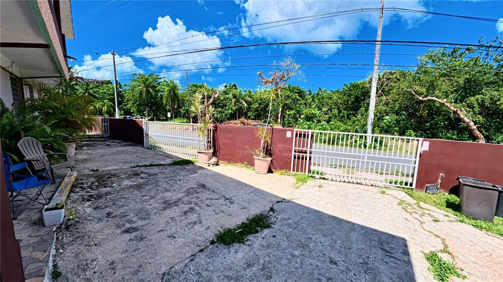 A concrete driveway leads to a gated entrance with a low wall and lush greenery — 696 CALLE PRINCIPAL UNIT 508, DORADO, PR