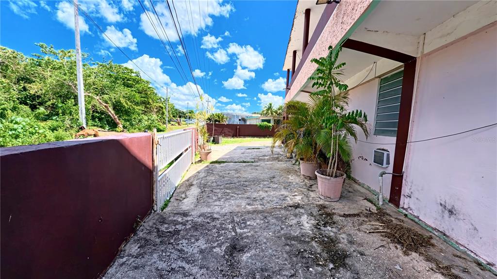 A concrete driveway leads alongside a pink building with potted plants and a metal gate — 696 CALLE PRINCIPAL UNIT 508, DORADO, PR