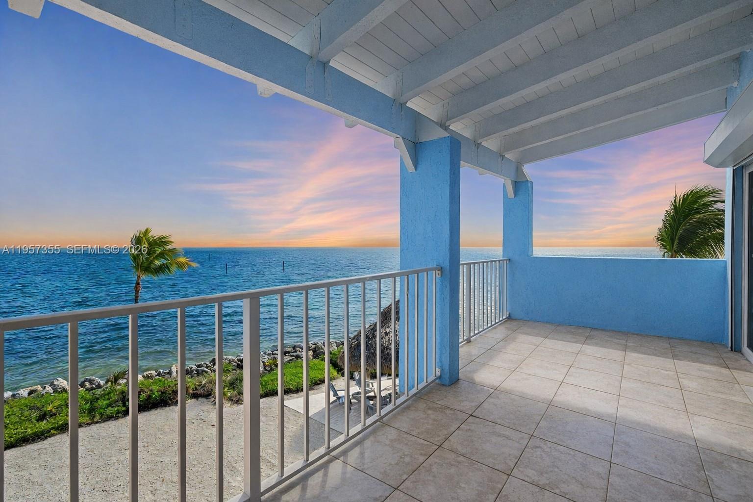 A tiled balcony with blue pillars overlooks the ocean at sunset — 1501 Ocean Bay Dr # A1, Key Largo FL 33037, KEY LARGO, FL