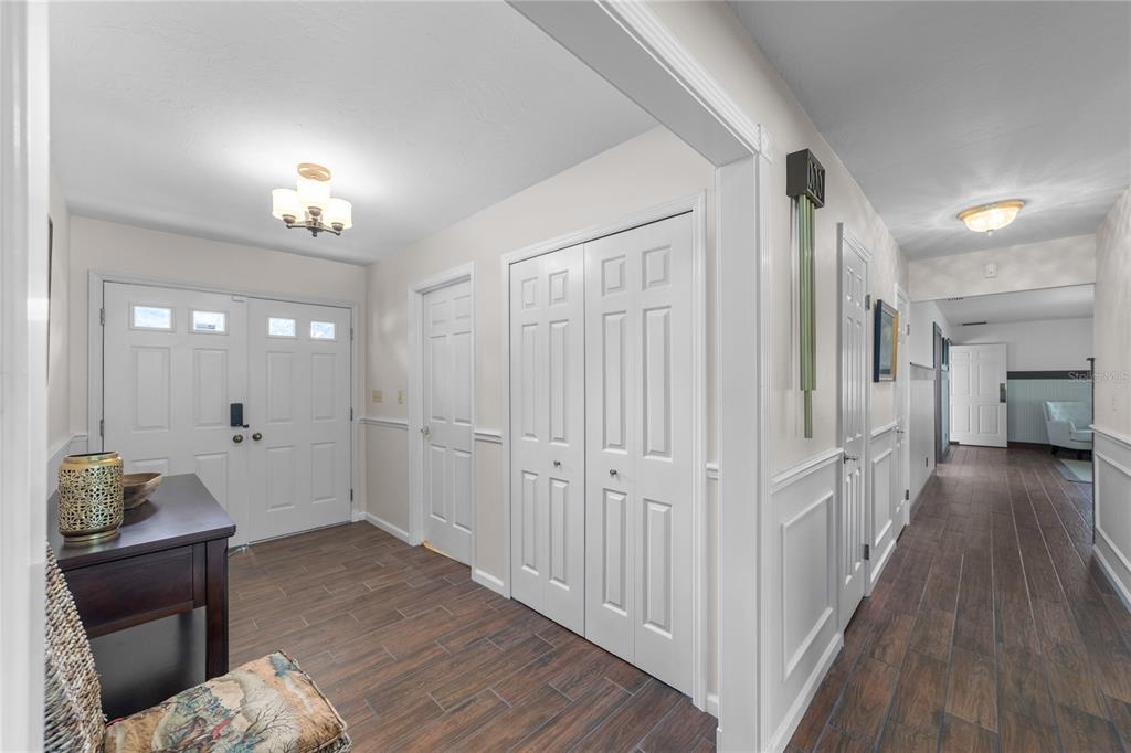 A foyer with wood-look tile flooring, white paneled doors, and a hallway leading to another room — 5310 NW 78TH COURT, OCALA, FL