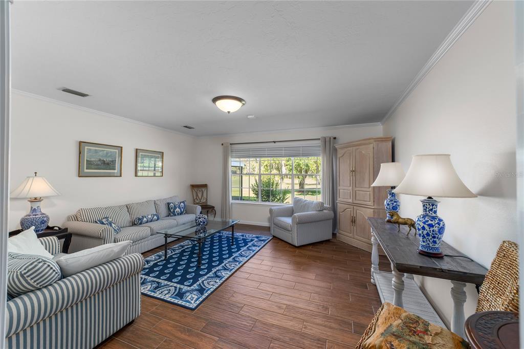 A living room features striped furniture, a blue patterned rug, and wood-look tile flooring — 5310 NW 78TH COURT, OCALA, FL
