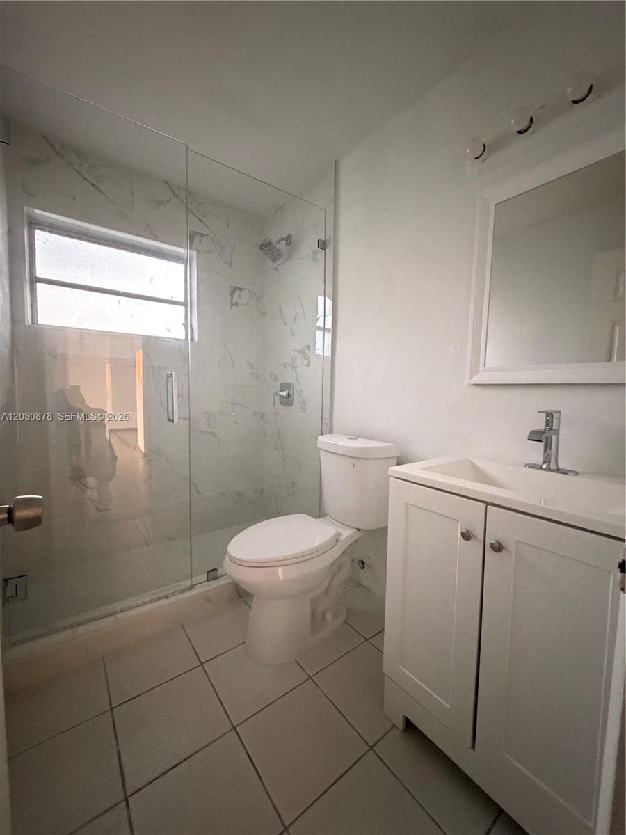 A bathroom features a glass-enclosed shower with marble-look tile, a white vanity, and a toilet — 7250 SW 94th Pl # B8, Miami FL 33173, MIAMI, FL
