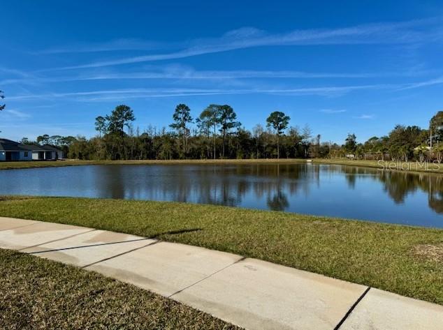 A concrete sidewalk borders a grassy lawn overlooking a pond with a treeline in the background — 191 PURCELL DRIVE, ORLANDO, FL
