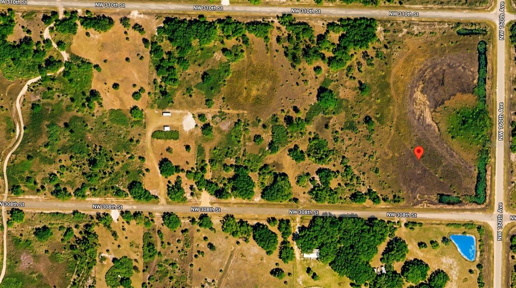 An aerial view shows a large, undeveloped, wooded lot bordered by two dirt roads — 16057 NW 308TH STREET, OKEECHOBEE, FL