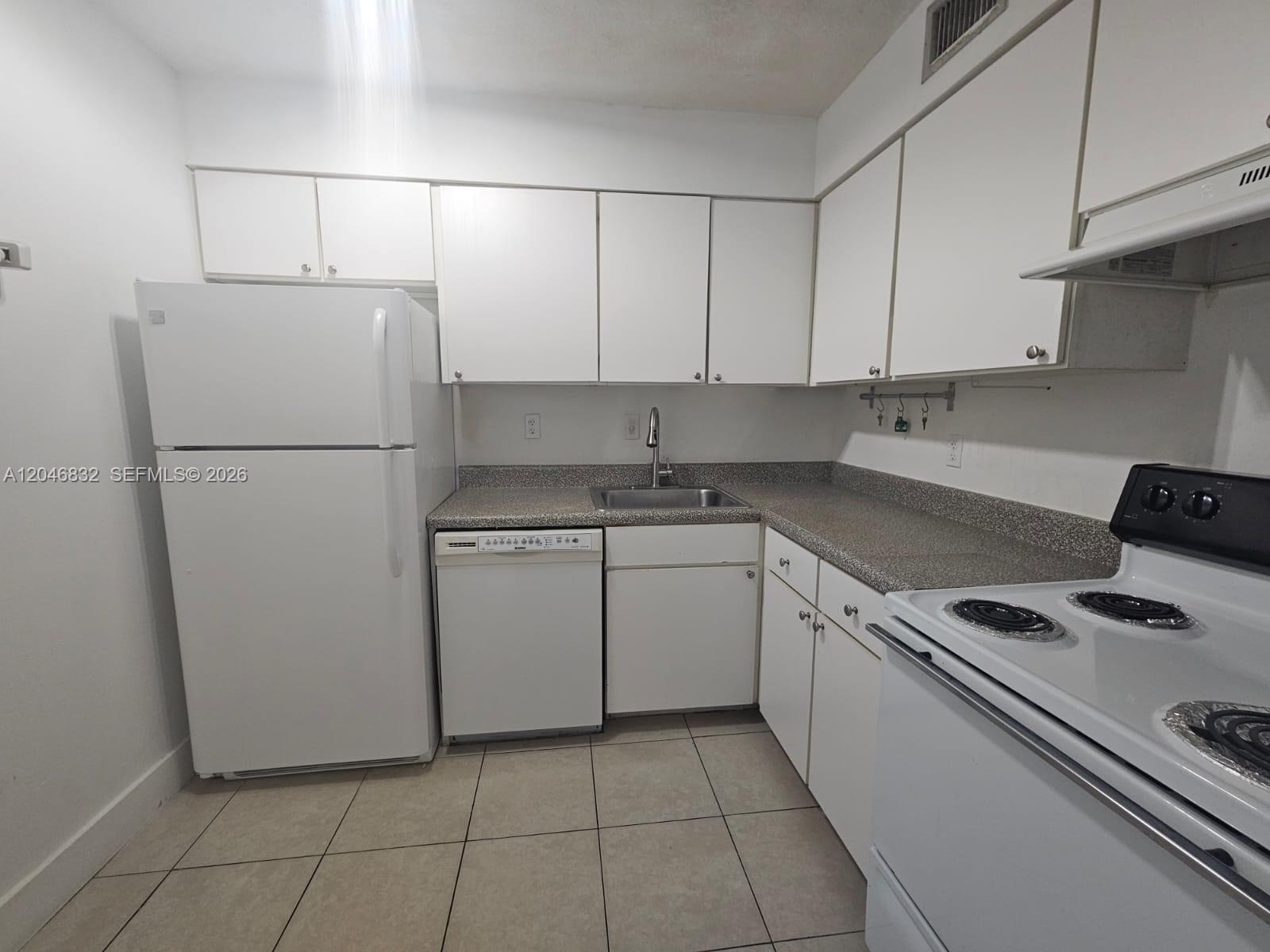 A kitchen features white cabinets, white appliances, and speckled countertops over tiled flooring — 4900 NW 79th Ave # 206, Doral FL 33166, DORAL, FL