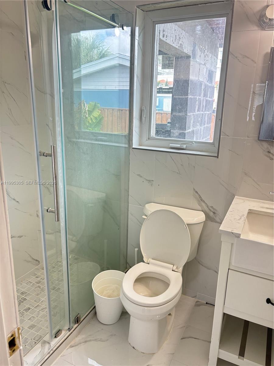 A bathroom features a glass-enclosed shower, a white toilet, and a vanity with marble-look tiles — 2951 SW 23rd St # 2, Miami FL 33145, MIAMI, FL