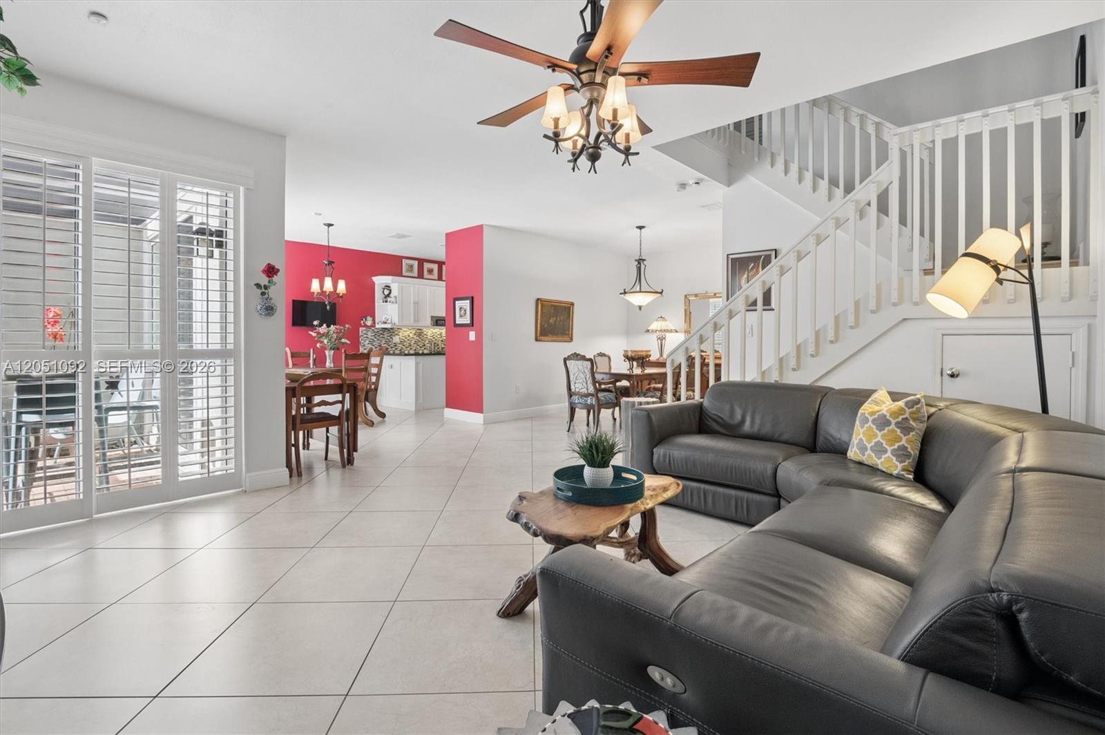 A living room with a grey sectional sofa, tile floors, and an open-concept kitchen area — 1140 Weeping Willow Way, Hollywood FL 33019, HOLLYWOOD, FL