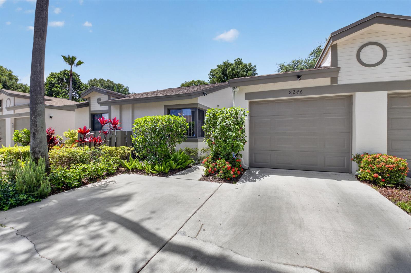 A single-story house with a concrete driveway, a gray garage door, and landscaped front gardens — 8246 Springview Terrace, Boca Raton FL 33496, BOCA RATON, FL