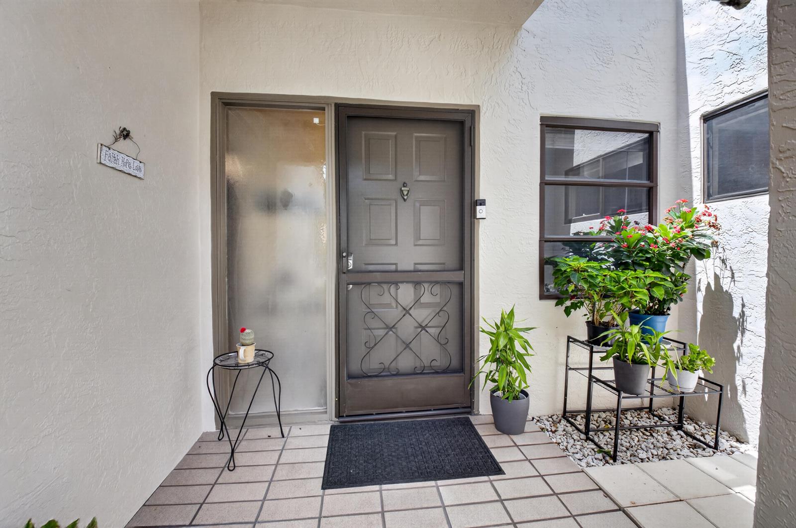 An exterior entryway features a brown storm door, a frosted sidelight, and several potted plants — 8246 Springview Terrace, Boca Raton FL 33496, BOCA RATON, FL