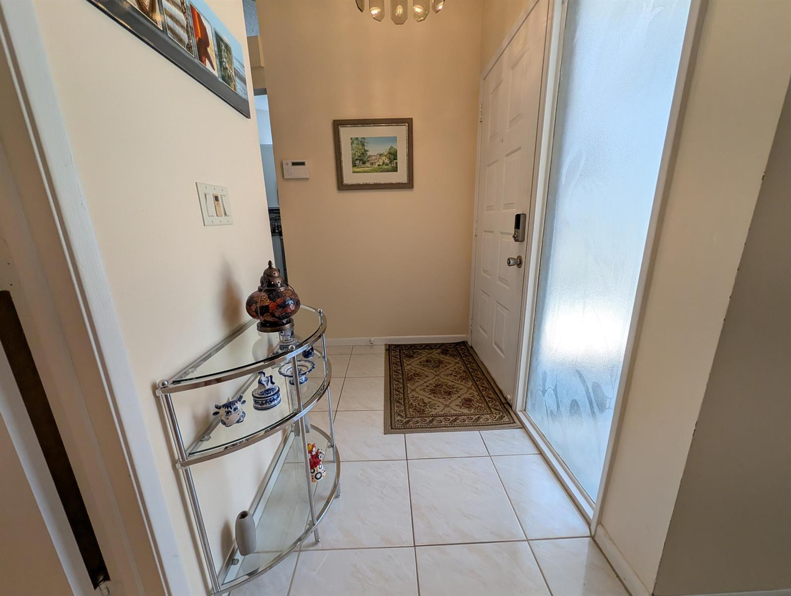 A tiled entryway features a glass console table, a framed picture, and a white door — 8246 Springview Terrace, Boca Raton FL 33496, BOCA RATON, FL