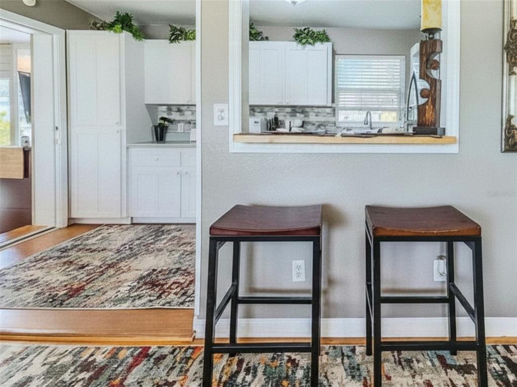 A kitchen pass-through window with a wooden ledge overlooks a room with two bar stools — 3114 ESPERANZA AVENUE, DAYTONA BEACH SHORES, FL
