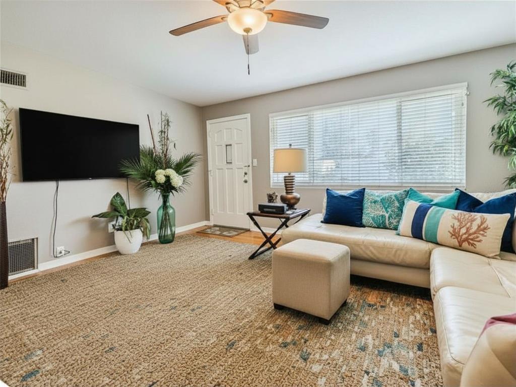 A living room features a white sectional sofa, a textured area rug, and a wall-mounted television — 3114 ESPERANZA AVENUE, DAYTONA BEACH SHORES, FL