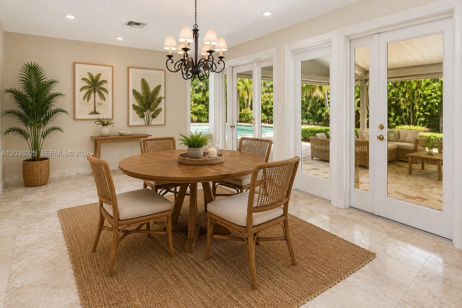 A dining room features a round wooden table, rattan chairs, and glass doors to a patio — 1030 Polk St, Hollywood FL 33019, HOLLYWOOD, FL