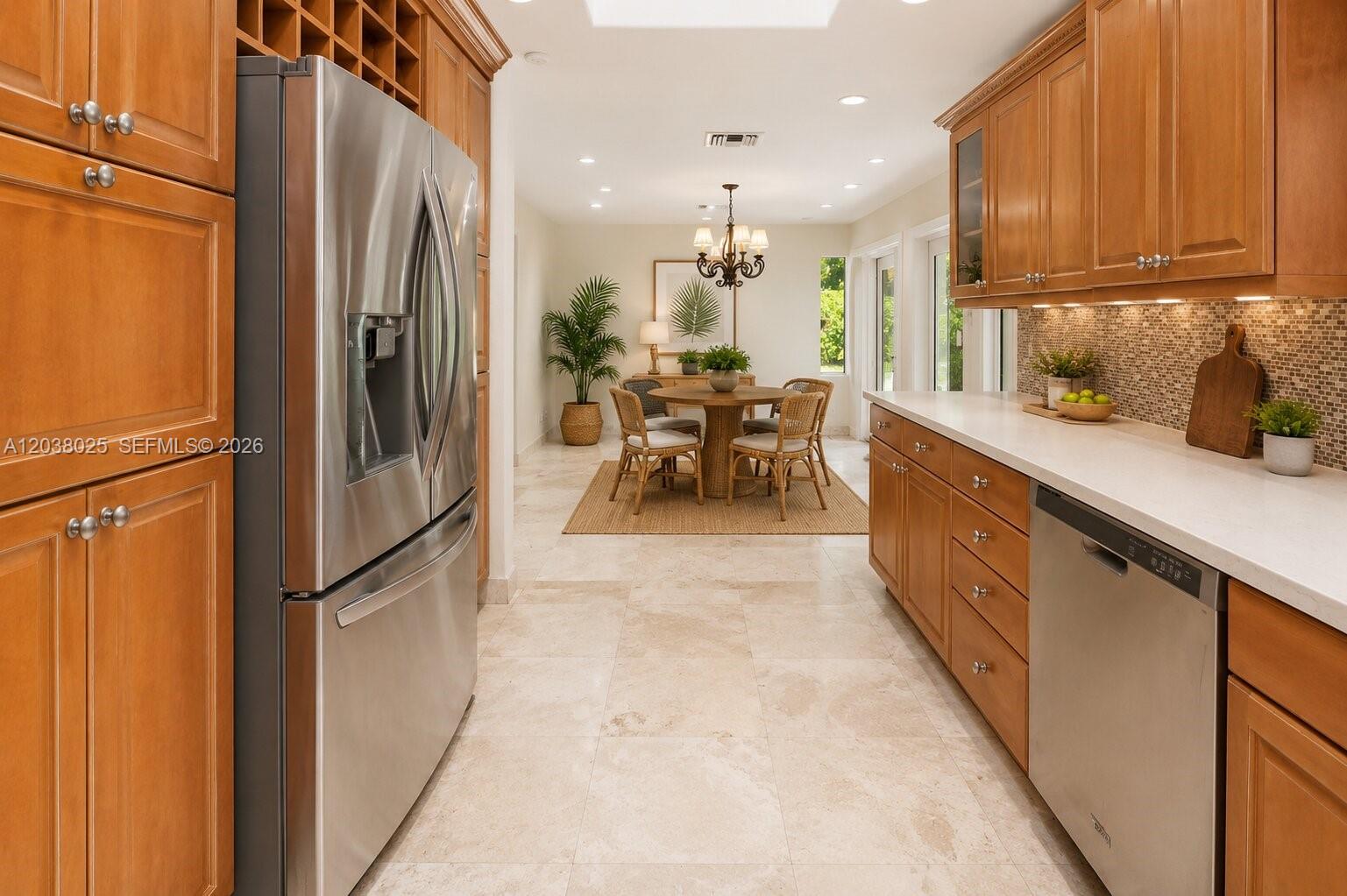 A kitchen with wood cabinets and stainless steel appliances opens into a dining area — 1030 Polk St, Hollywood FL 33019, HOLLYWOOD, FL