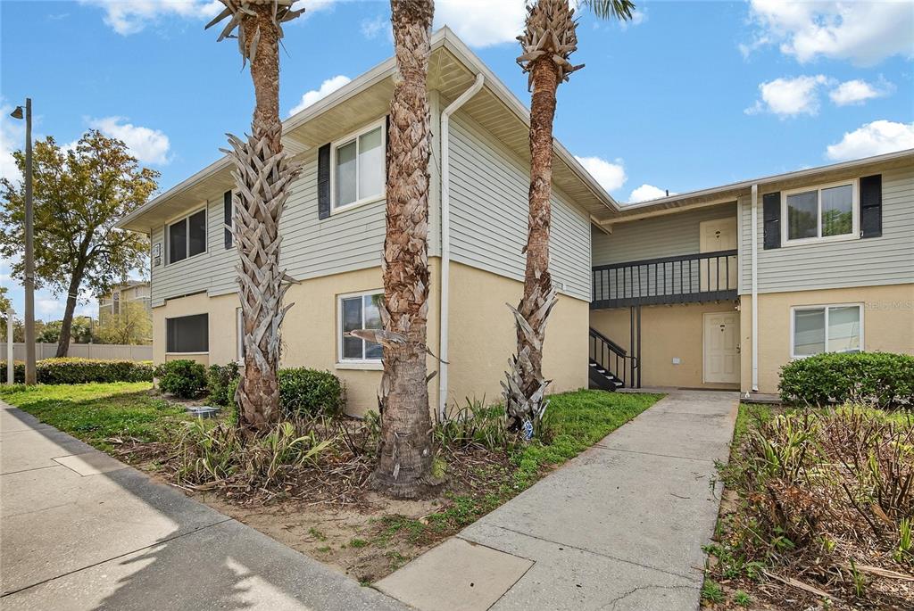 A two-story apartment building exterior features tan stucco, light siding, and two palm trees — 202 RED MAPLE PLACE UNIT 202, BRANDON, FL