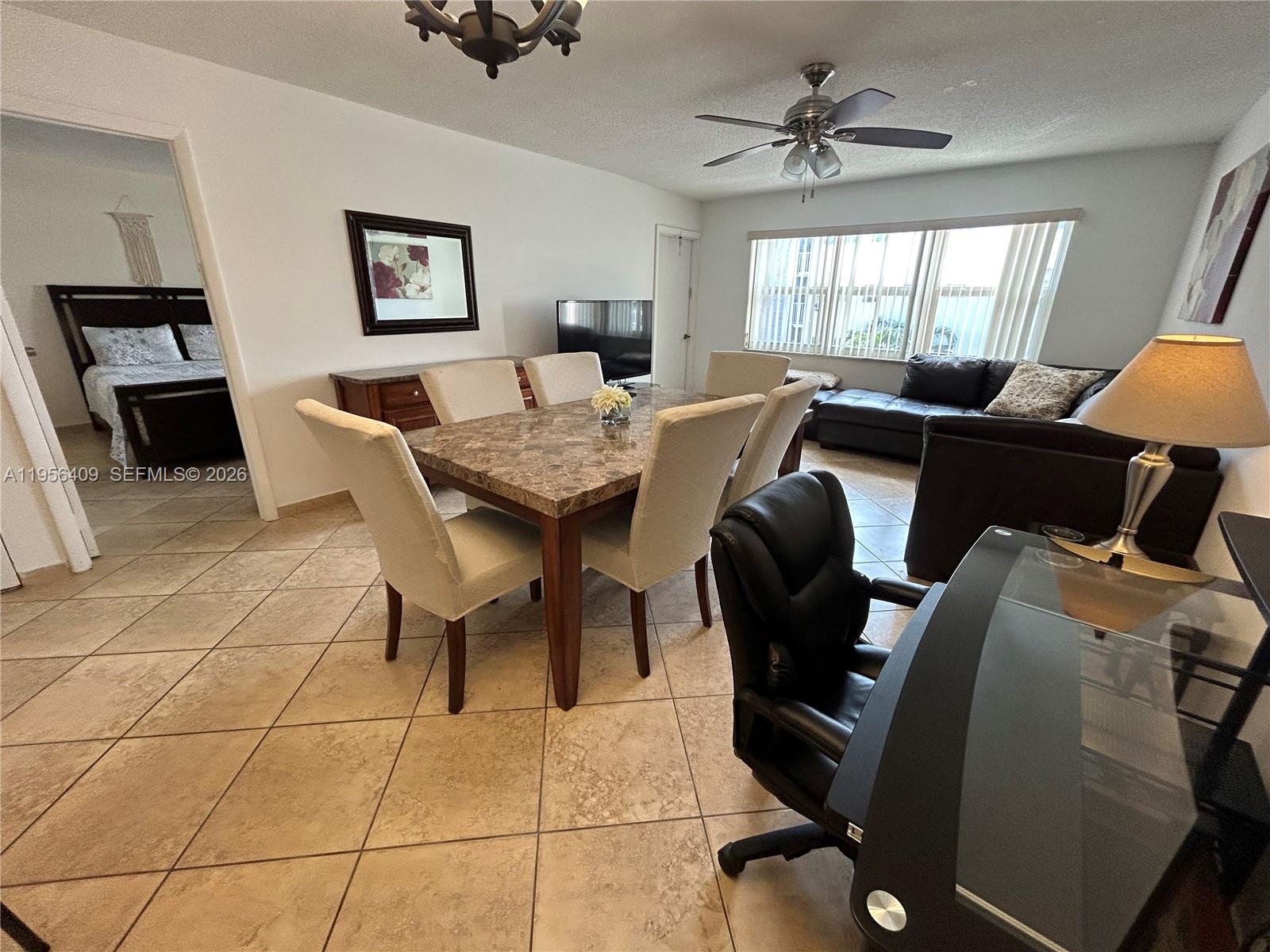 An open-concept living and dining area features tile flooring, a marble-topped table, and furniture — 410 SE 2nd St # 308, Hallandale Beach FL 33009, HALLANDALE BEACH, FL