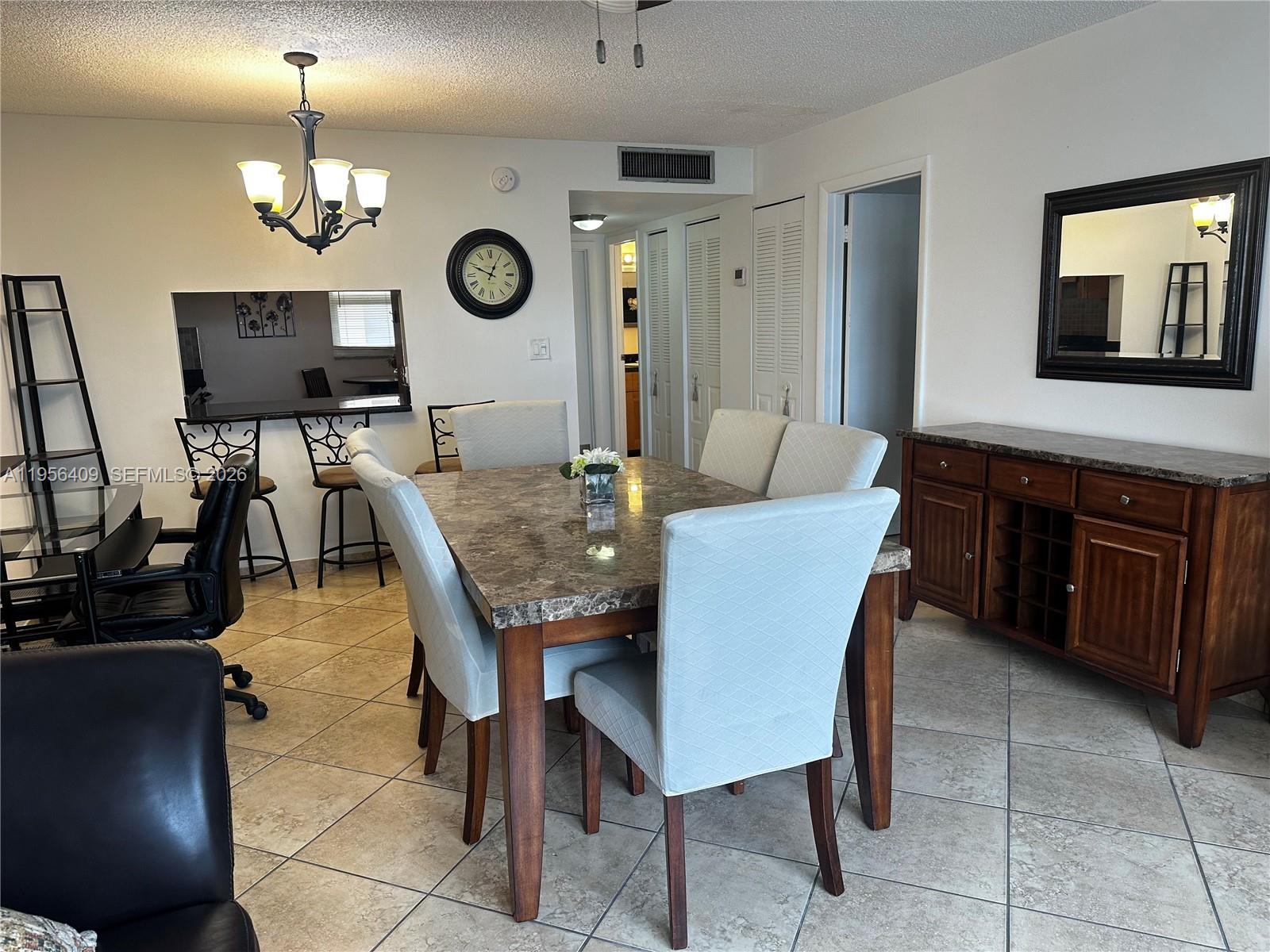 A dining room features a marble-topped table, upholstered chairs, a wooden sideboard, and tile flooring — 410 SE 2nd St # 308, Hallandale Beach FL 33009, HALLANDALE BEACH, FL