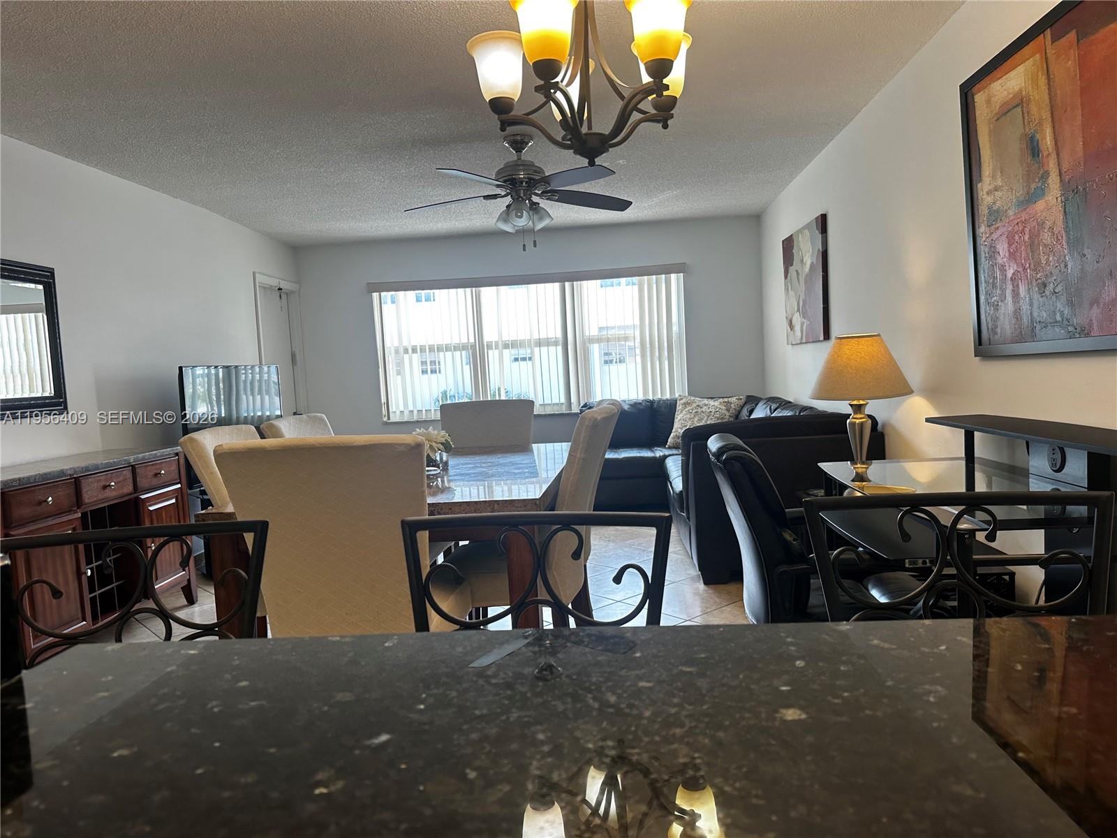 A dining area and living room feature a chandelier, ceiling fan, and dark wood furniture — 410 SE 2nd St # 308, Hallandale Beach FL 33009, HALLANDALE BEACH, FL