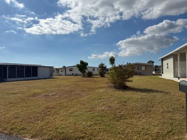 A vacant, grassy lot sits between several manufactured homes under a partly cloudy blue sky — 224 EL PRADO, NORTH PORT, FL