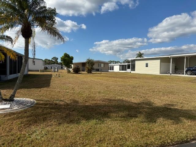 A grassy lot sits between several manufactured homes under a blue sky with scattered clouds — 224 EL PRADO, NORTH PORT, FL