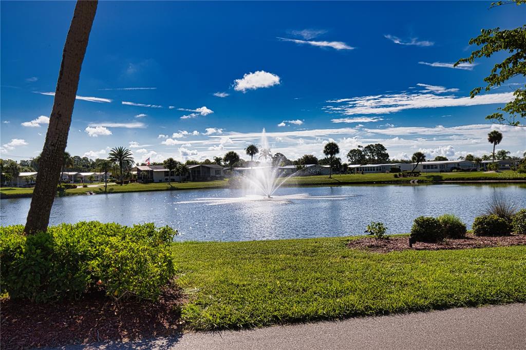 A fountain sprays water in the center of a lake surrounded by houses and palm trees — 224 EL PRADO, NORTH PORT, FL