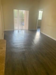 An empty room with dark wood-look flooring and a sliding glass door with vertical blinds — 3251 Sabal Palm Manor # 207, Davie FL 33024, DAVIE, FL