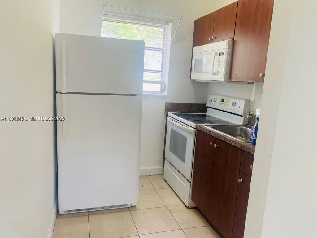 A small kitchen features a white refrigerator, a white stove, and dark wood cabinets — 401 N DIXIE HWY # 6, Hallandale Beach FL 33009, HALLANDALE BEACH, FL
