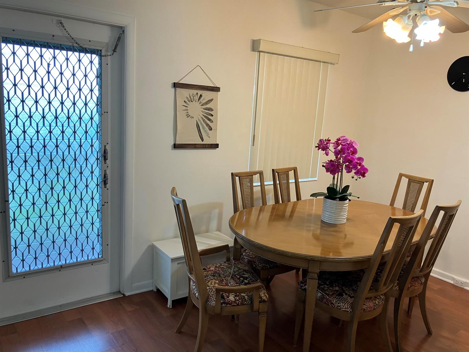 A dining room with a wooden table, six chairs, an orchid centerpiece, and a security door — 103 Prescott E, Deerfield Beach FL 33442, DEERFIELD BEACH, FL